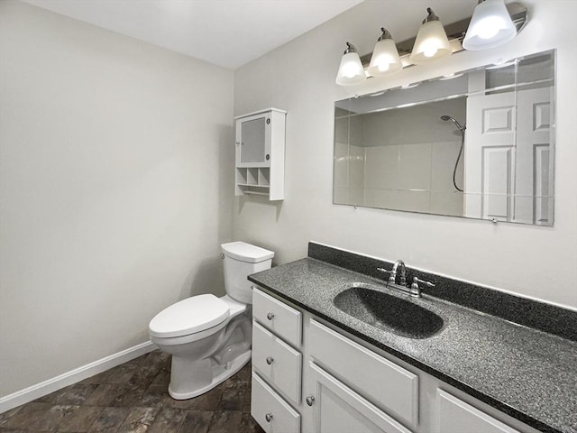 bathroom with a shower, baseboards, toilet, and vanity