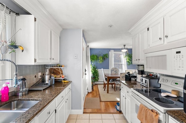 kitchen featuring light tile patterned floors, white appliances, white cabinets, and dark stone countertops