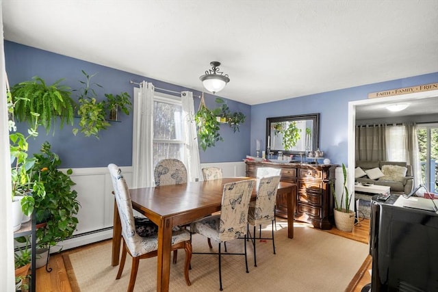 dining space with a baseboard radiator and light wood-type flooring