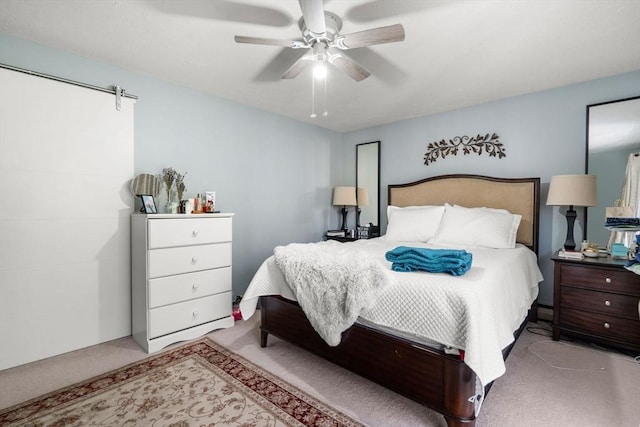 carpeted bedroom featuring ceiling fan and a barn door