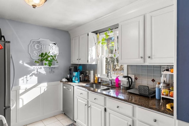 kitchen with appliances with stainless steel finishes, tasteful backsplash, white cabinetry, sink, and dark stone counters