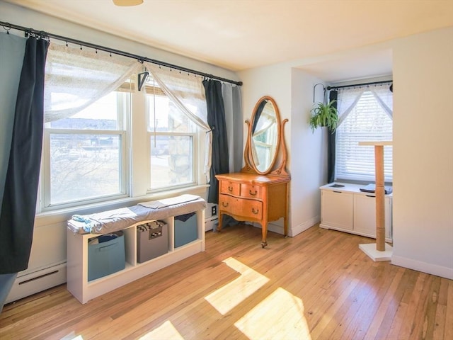 living area featuring baseboard heating, light wood-style flooring, and baseboards