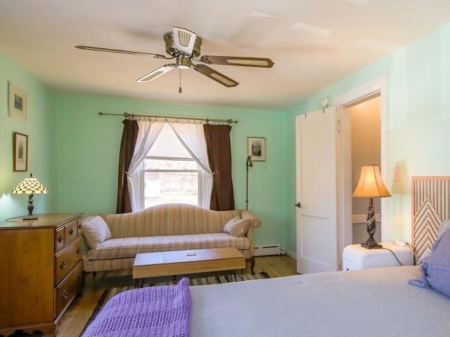 bedroom with a baseboard heating unit, ceiling fan, and wood finished floors