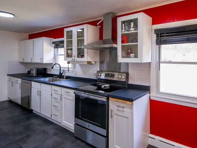 kitchen featuring a sink, a baseboard heating unit, dark countertops, appliances with stainless steel finishes, and wall chimney range hood