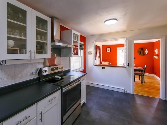 kitchen featuring glass insert cabinets, stainless steel electric stove, dark countertops, wall chimney range hood, and a baseboard radiator