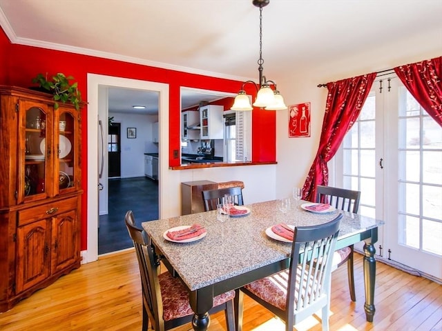 dining room featuring light wood-type flooring, baseboards, and ornamental molding