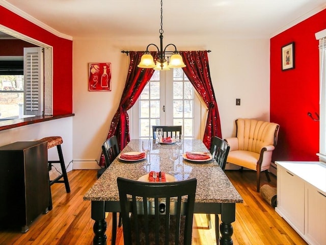 dining space featuring an inviting chandelier, baseboards, wood-type flooring, and ornamental molding