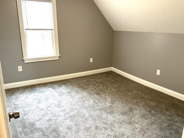 additional living space with lofted ceiling, baseboards, and dark colored carpet