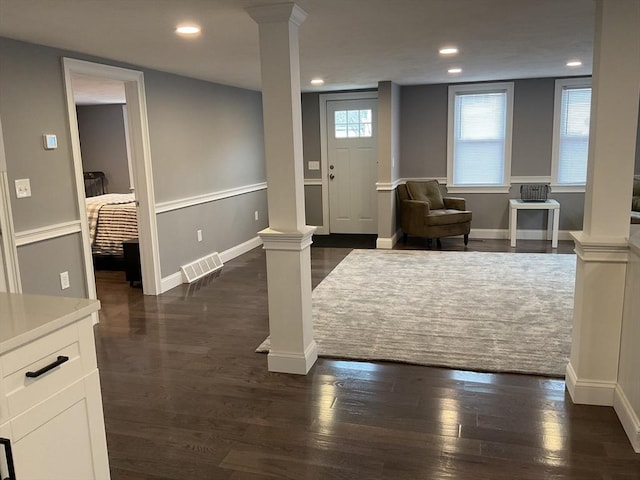 entrance foyer with decorative columns and dark wood-type flooring