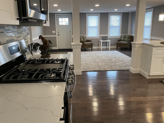 kitchen featuring gas stove, tasteful backsplash, dark wood finished floors, and ornate columns