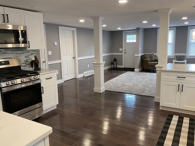 kitchen with ornate columns, dark wood-type flooring, open floor plan, and appliances with stainless steel finishes