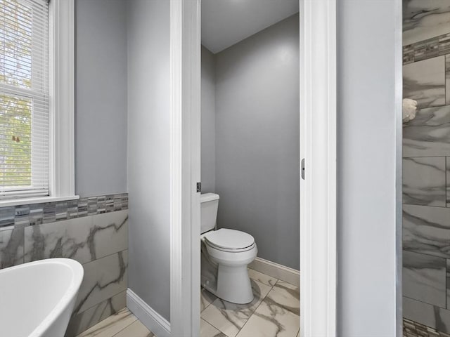 851 Forest St, North Andover, MA 01845 - bathroom featuring marble finish floors, toilet, a freestanding bath, tile walls, and baseboards