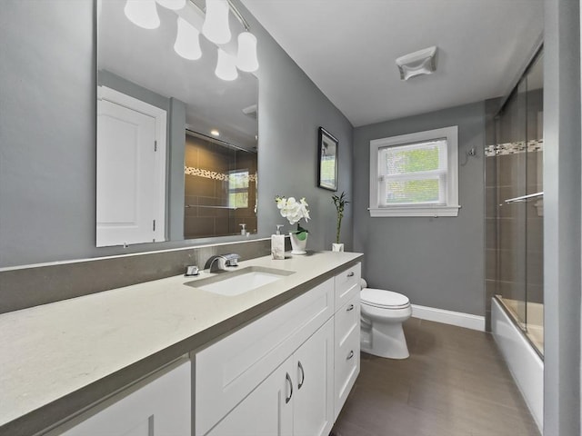 851 Forest St, North Andover, MA 01845 - bathroom with vanity, toilet, wood finished floors, enclosed tub / shower combo, and baseboards