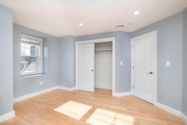 unfurnished bedroom with light hardwood / wood-style floors and a closet