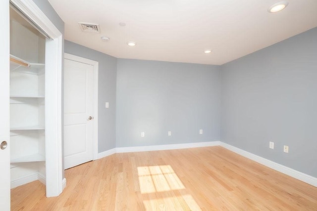 unfurnished room featuring built in shelves and light hardwood / wood-style floors