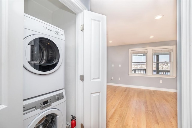 laundry room with stacked washer / dryer and light wood-type flooring