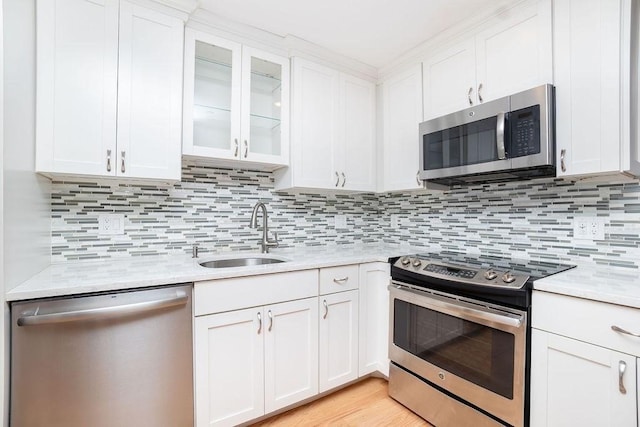 kitchen with tasteful backsplash, appliances with stainless steel finishes, sink, and white cabinets