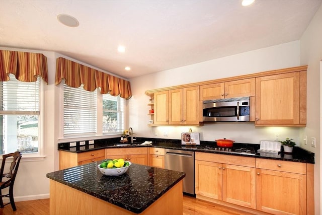 kitchen with a center island, sink, dark stone countertops, light wood-type flooring, and stainless steel appliances