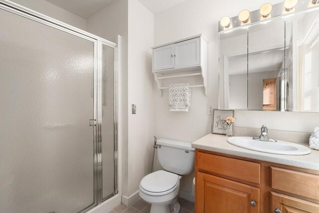 bathroom featuring tile patterned floors, vanity, toilet, and an enclosed shower