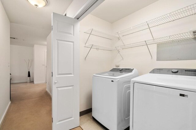 clothes washing area featuring washing machine and dryer and light colored carpet