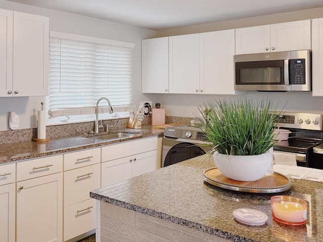 kitchen featuring stainless steel microwave, stone countertops, a sink, and white cabinetry