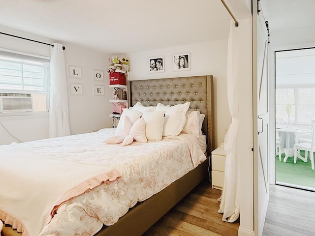 bedroom with wood finished floors, cooling unit, and multiple windows