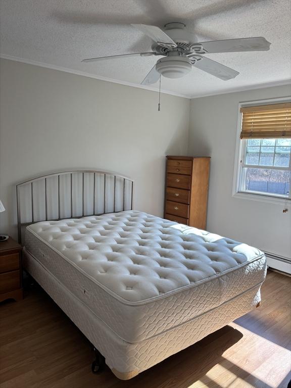 12 Candlewood Ln Unit 2-2, Dennis, MA 02639 - bedroom with dark wood-type flooring, crown molding, a ceiling fan, and a textured ceiling