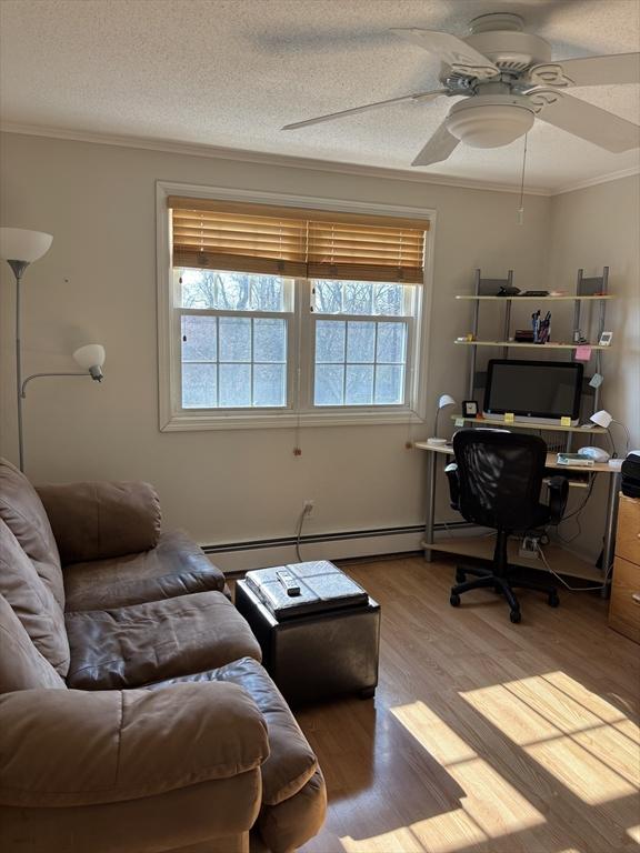 12 Candlewood Ln Unit 2-2, Dennis, MA 02639 - office area with a textured ceiling, crown molding, a baseboard radiator, ceiling fan, and wood finished floors