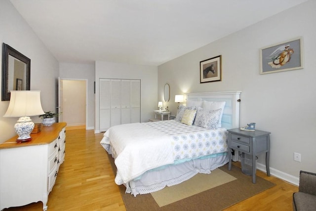 bedroom with baseboards, light wood finished floors, and a closet