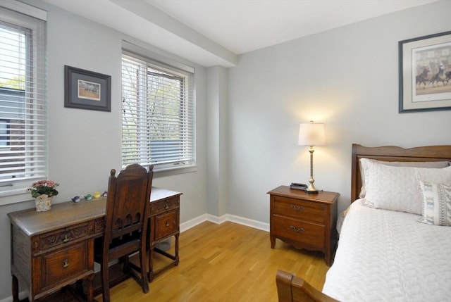 bedroom with baseboards, multiple windows, and light wood-style flooring