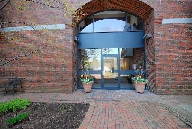 entrance to property with brick siding and a patio area