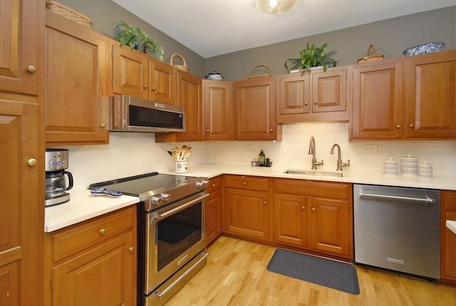 kitchen featuring light countertops, stainless steel appliances, a sink, and light wood finished floors