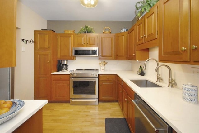 kitchen featuring light wood-type flooring, a sink, appliances with stainless steel finishes, and light countertops