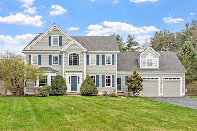 colonial-style house featuring an attached garage, driveway, and a front lawn