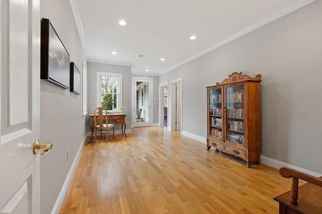 hallway featuring crown molding, light wood finished floors, and baseboards