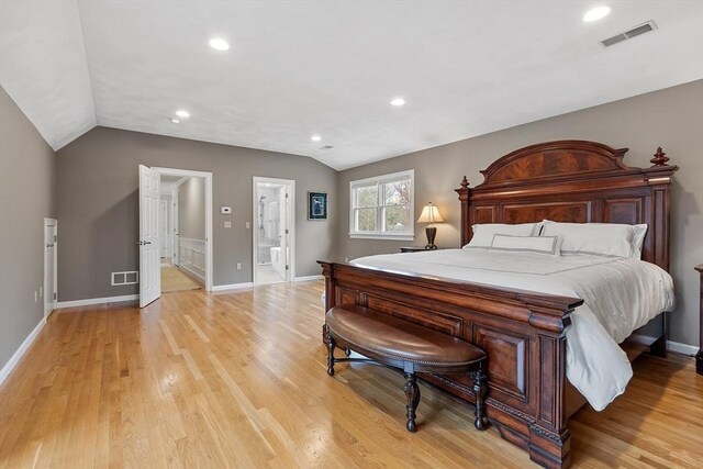 bedroom featuring ensuite bathroom, vaulted ceiling, light wood finished floors, and visible vents