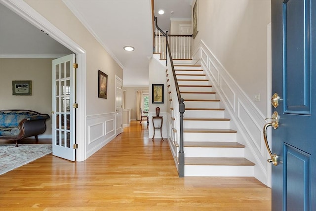 entrance foyer featuring crown molding, a decorative wall, stairway, recessed lighting, and light wood-style flooring