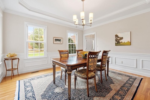 dining room featuring an inviting chandelier, light wood finished floors, crown molding, and visible vents