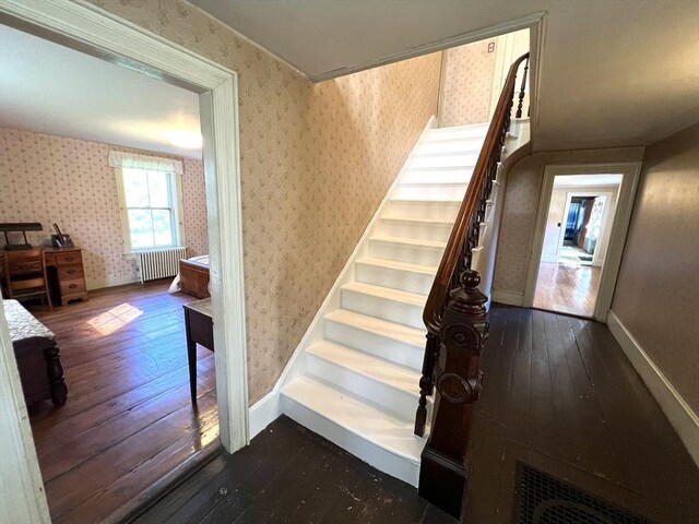 hallway with dark hardwood / wood-style flooring, radiator heating unit, and a chandelier