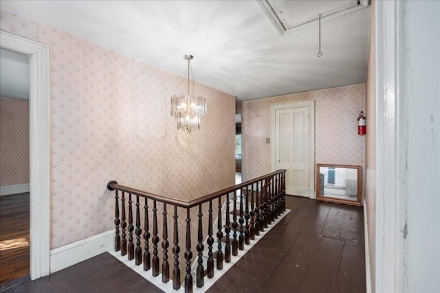 corridor featuring dark wood-type flooring and a notable chandelier