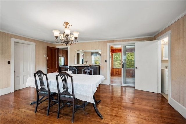 dining room featuring a notable chandelier, ornamental molding, and dark wood-type flooring