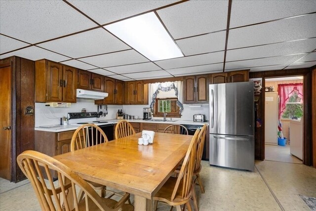 kitchen with radiator, dishwasher, wood walls, and a healthy amount of sunlight