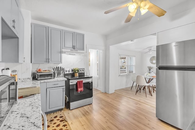 kitchen featuring light stone countertops, light wood-type flooring, stainless steel appliances, and gray cabinets