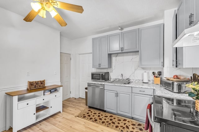 kitchen featuring ceiling fan, sink, range hood, light hardwood / wood-style floors, and appliances with stainless steel finishes