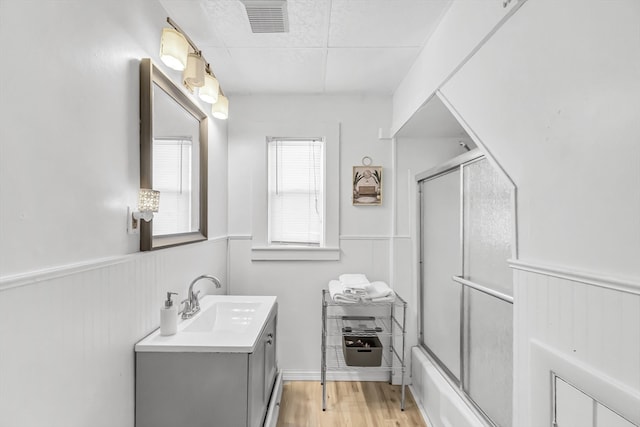 bathroom with hardwood / wood-style floors, vanity, and bath / shower combo with glass door