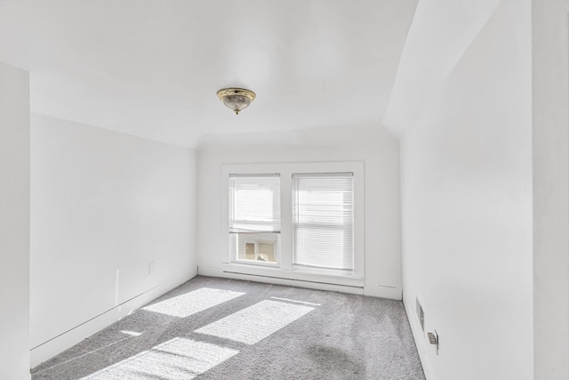 carpeted spare room with vaulted ceiling