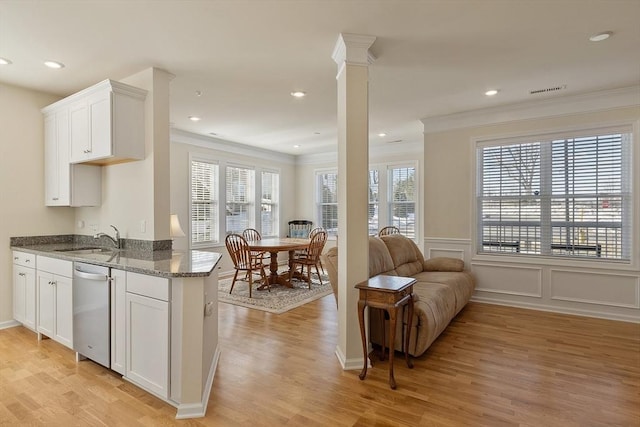 kitchen with dark stone counters, a sink, a healthy amount of sunlight, dishwasher, and ornate columns