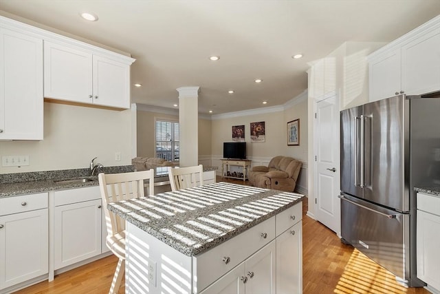 kitchen with decorative columns, high end refrigerator, light wood-style flooring, and a sink