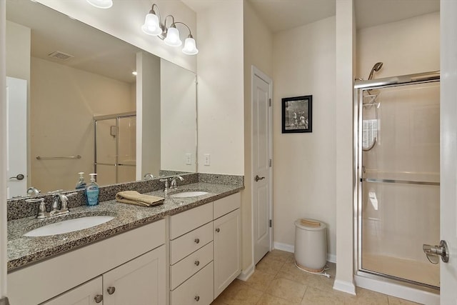 bathroom with double vanity, a stall shower, a sink, and tile patterned floors