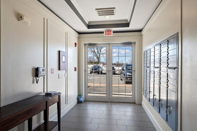 doorway to outside featuring visible vents, mail area, a tray ceiling, crown molding, and french doors